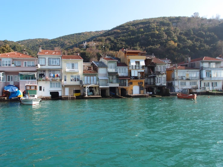 several large houses sitting on top of a hillside next to the water