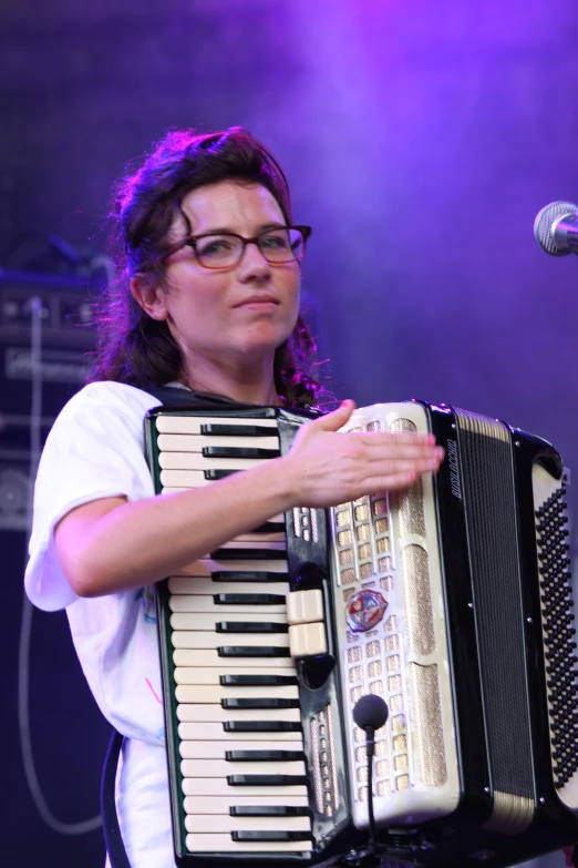 a woman with glasses is playing the accordion