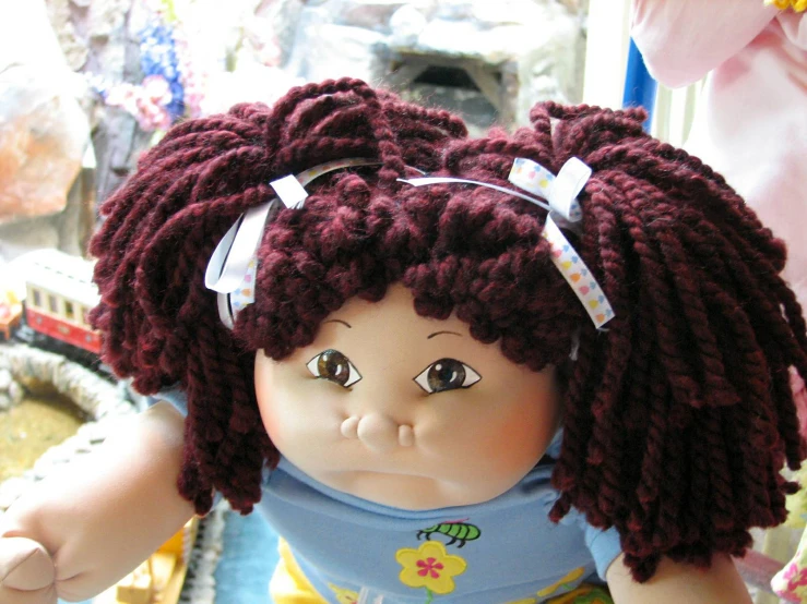 a doll wearing a sweater and a large knitted headband with a bow