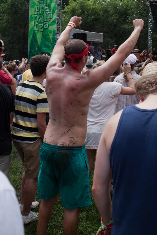 a man without his shirt and shorts is dancing while other people watch