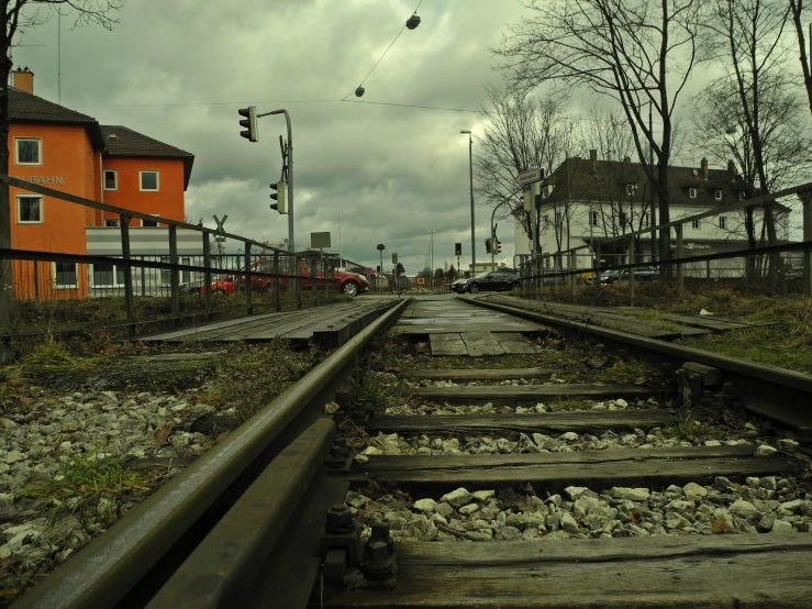 a rail road track with trees, bushes and houses in the background