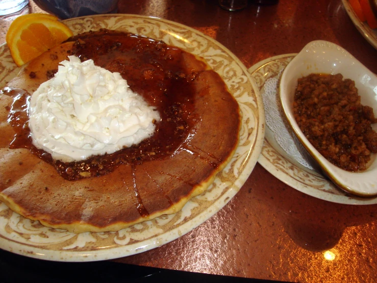 a table with two plates of food that have pancakes and other dessert items on them