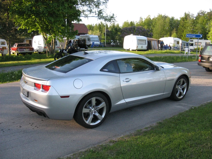 a silver sports car parked in a driveway near the street