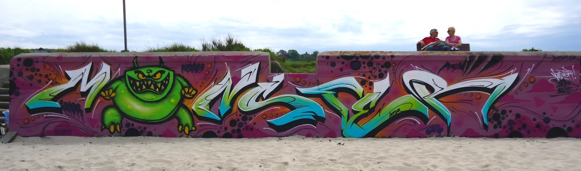 a graffiti covered wall sits in front of a beach