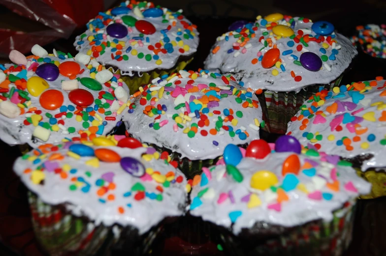 a table full of cupcakes with white frosting and sprinkles