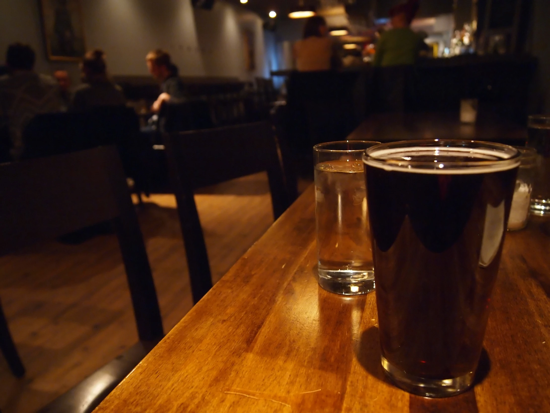 a wooden table with two tall clear glasses sitting on top