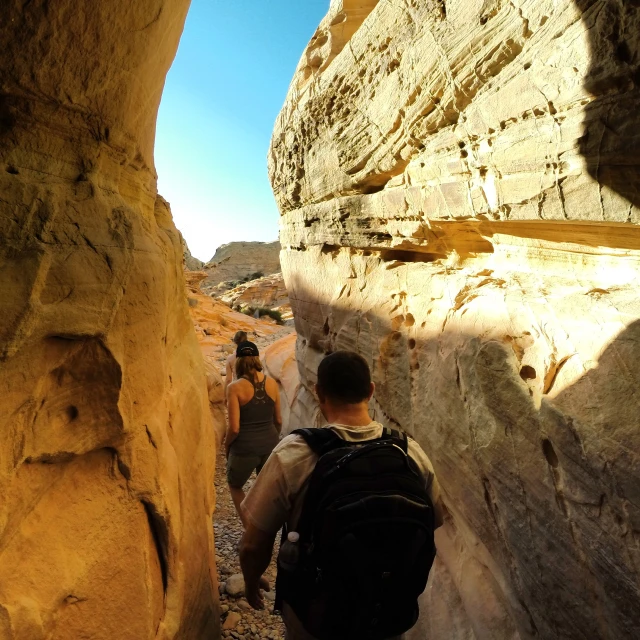 three hikers are ascending into the canyon in the desert