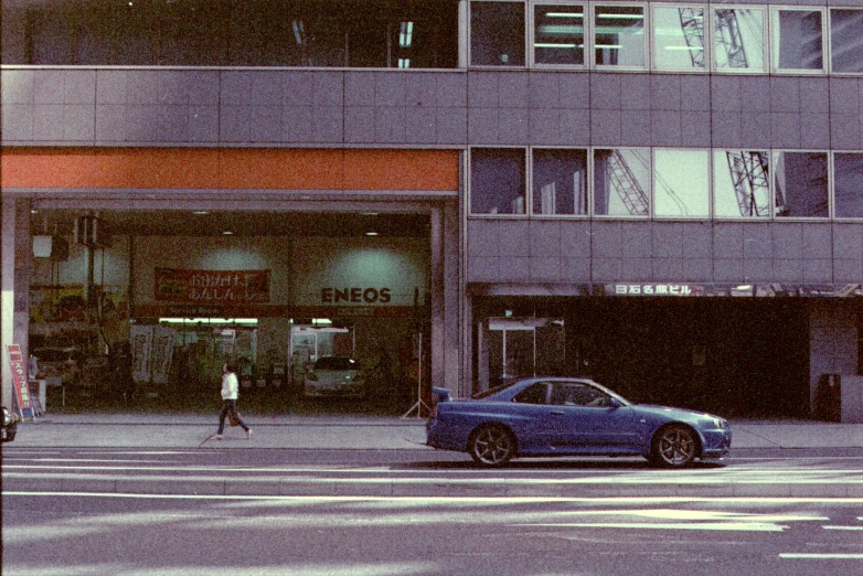 an automobile is parked near a building with multiple levels of windows