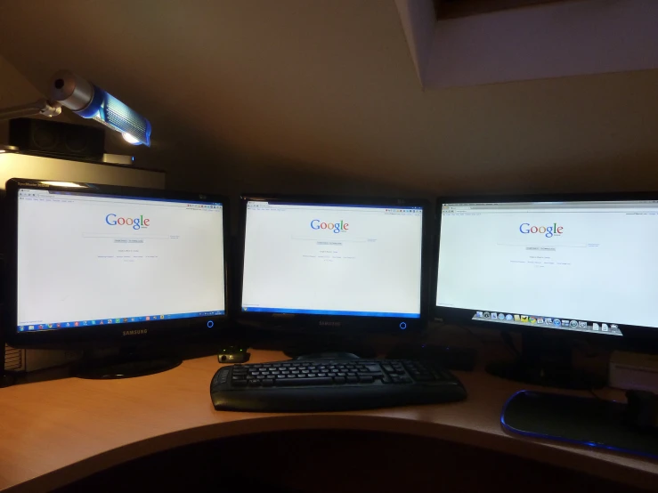 there is three computer screens on this desk