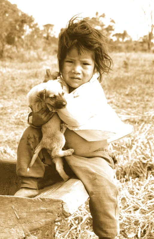 a child holding two stuffed animals on top of wooden post