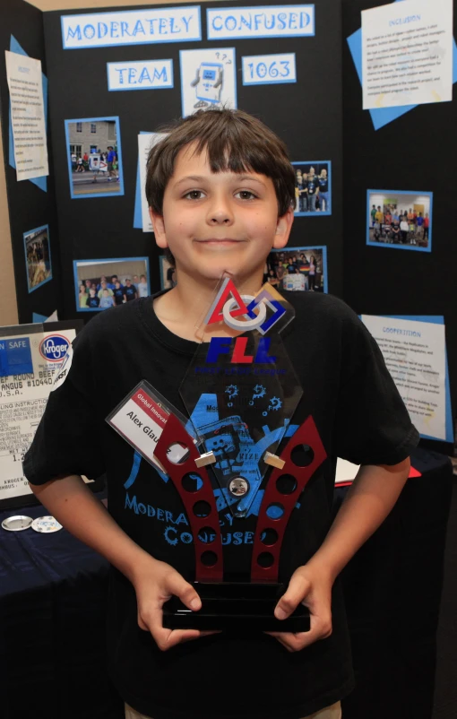 a boy holds an award plaque for his project