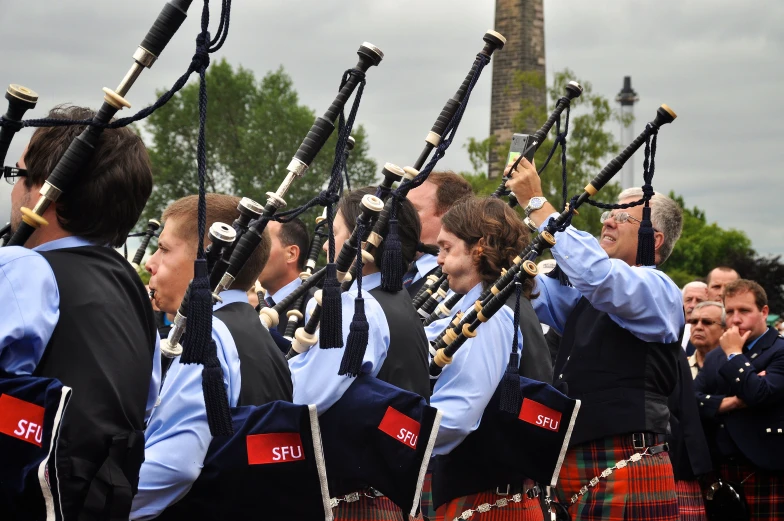 men in kilts holding sticks and looking at the ground