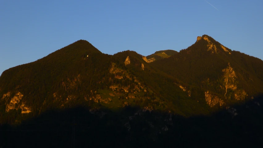 a mountain rising in the air with a plane flying above