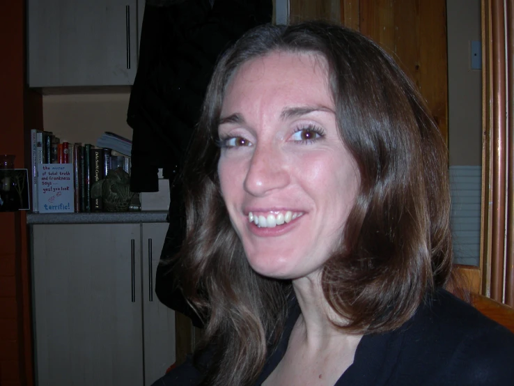 a woman with long brown hair smiling and wearing a blazer