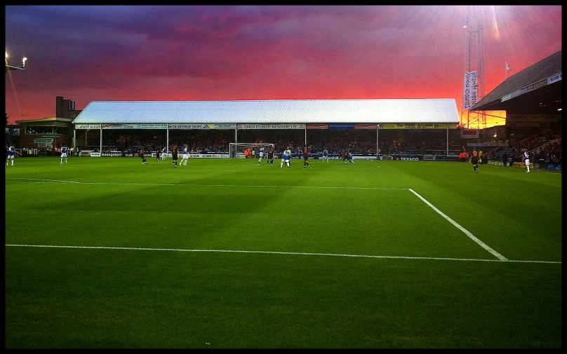 a soccer field with people on it, in the evening