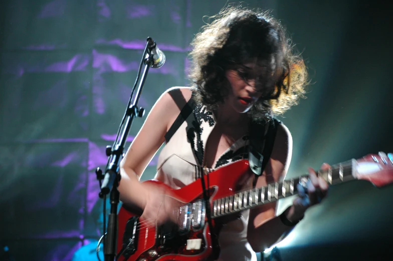 the girl is playing on the red guitar