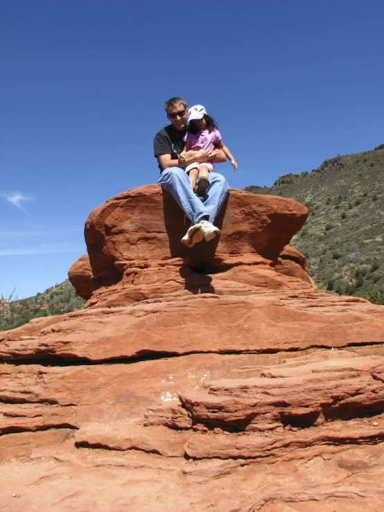 a man and woman are sitting on a rock