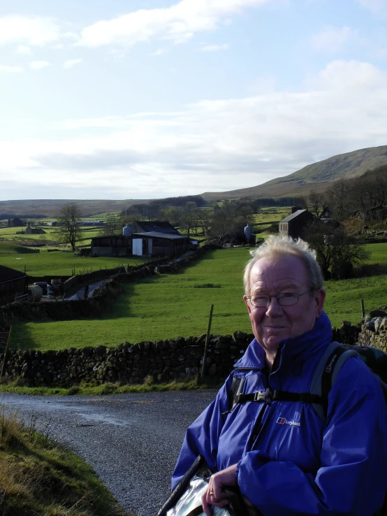 a man with a backpack on standing in front of a farm