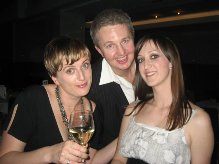 a woman holding a glass of wine with two men