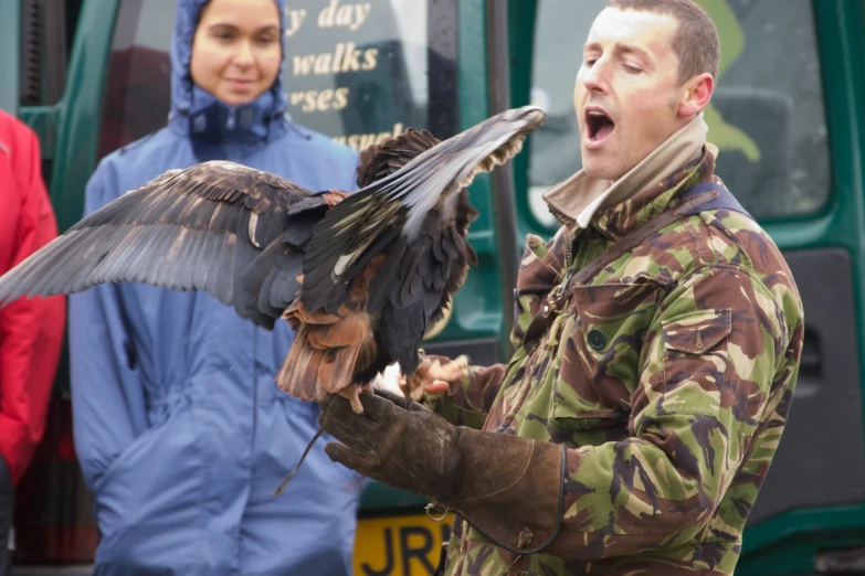 a man standing in front of people holding a bird