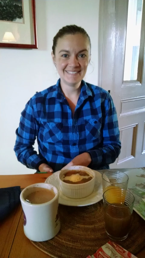 the smiling woman is eating soup and coffee