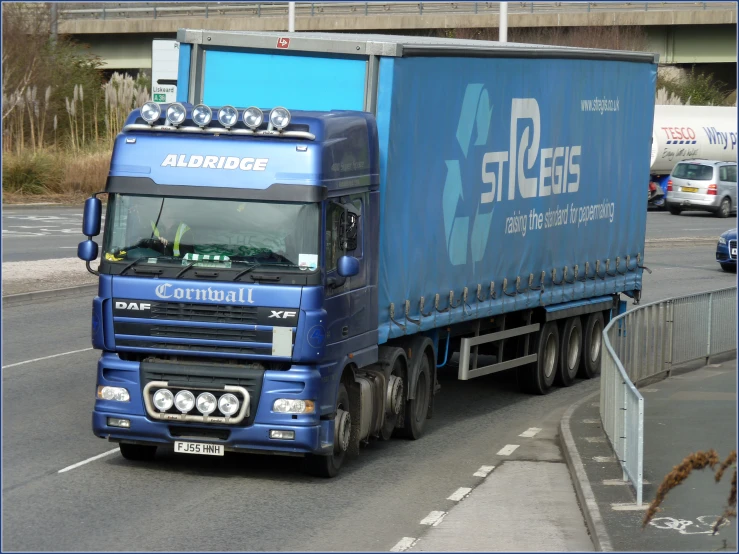 a blue semi truck is parked on a road near some buildings