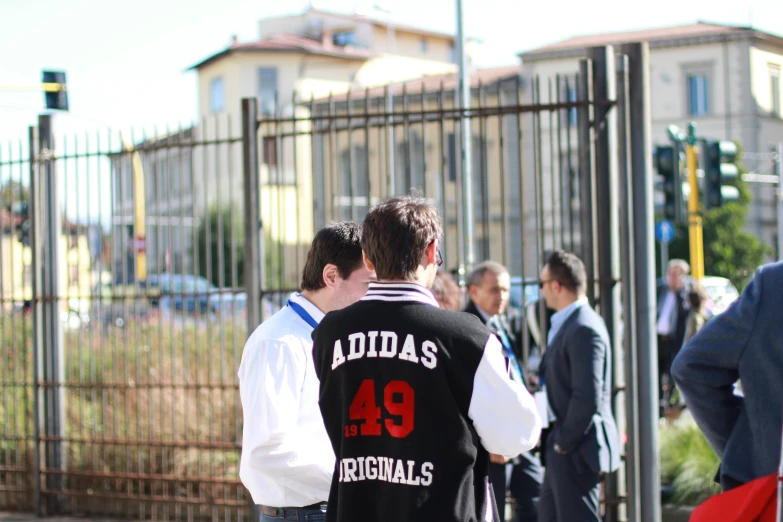 people are walking near a fence and some buildings