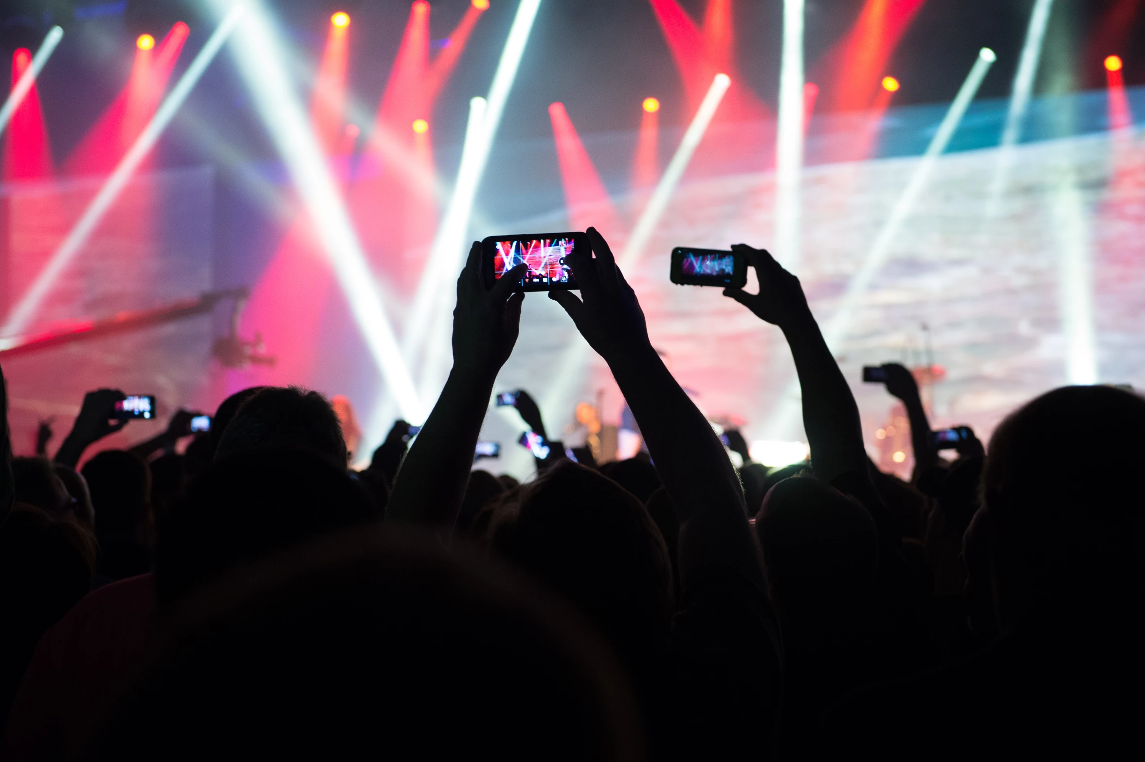 many people holding their cell phones up to take pictures