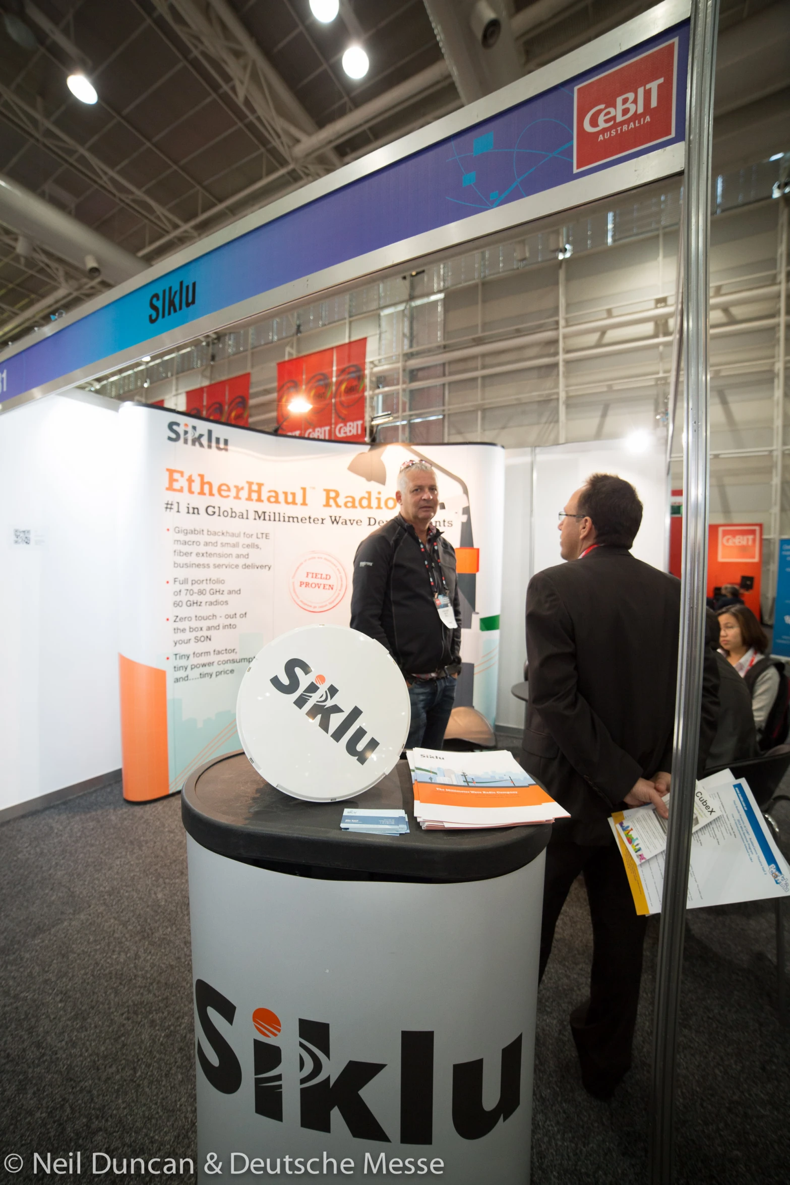 a couple of people standing at a booth talking