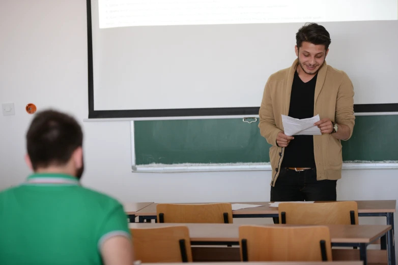 a man is reading a sheet of paper in a class room