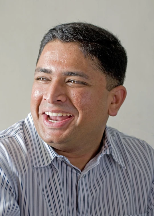 a smiling man wearing a striped shirt and a bow tie