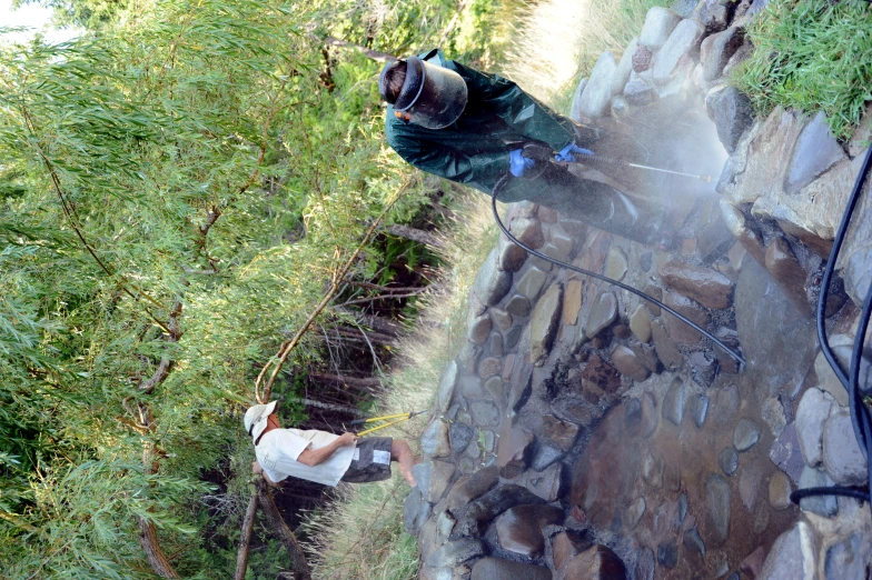 two people in work clothes standing in water with trees