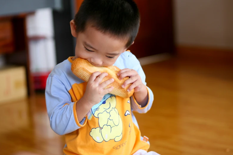 a little boy eating some corn on a wooden floor