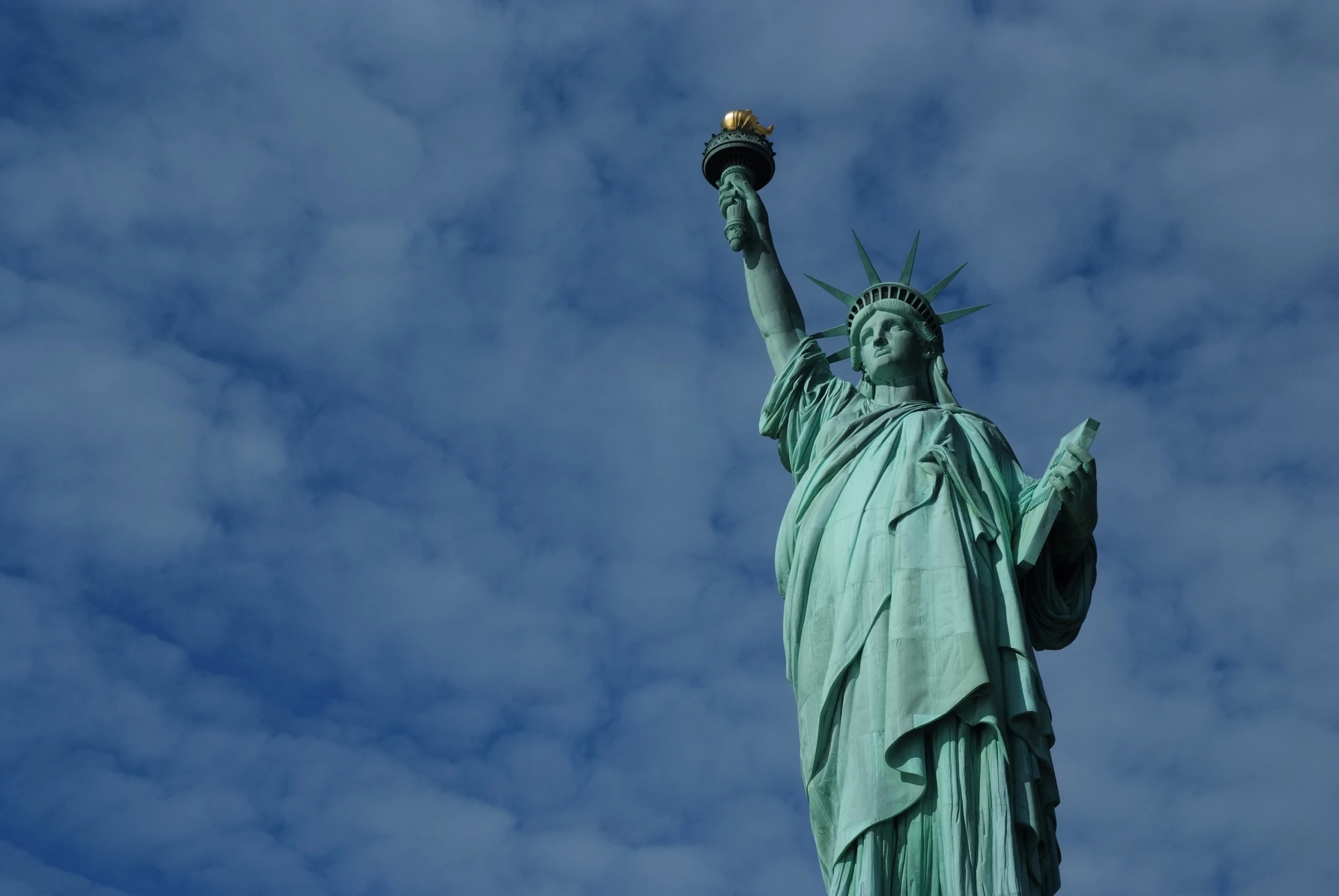 the statue of liberty is shown in front of a cloudy sky