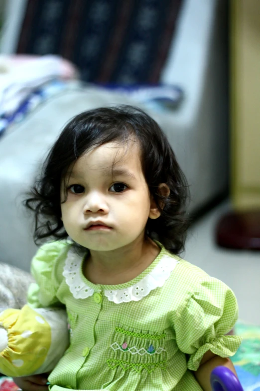 a little girl sitting on the floor with stuffed toys