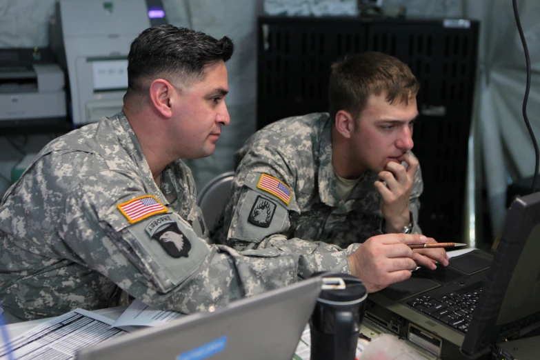 two military men look at soing on a computer