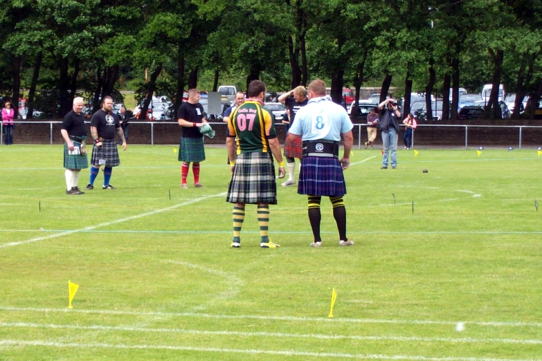 two scottish men are wearing kilts standing at the beginning of a line of flags