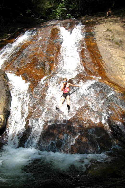 a woman in the water is playing on some rocks