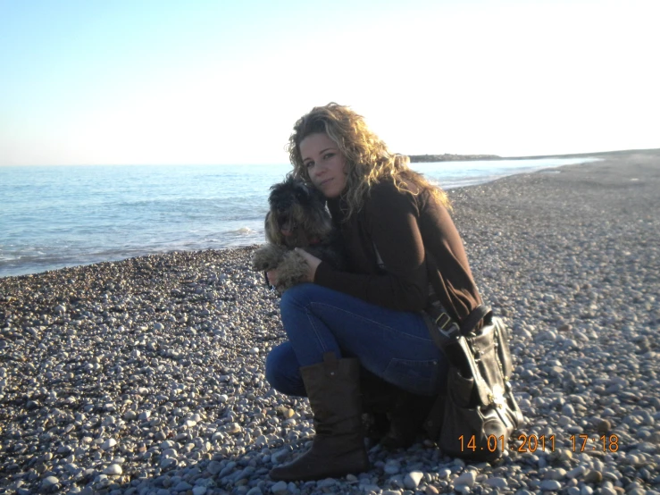 there is a woman that is holding a dog by the water