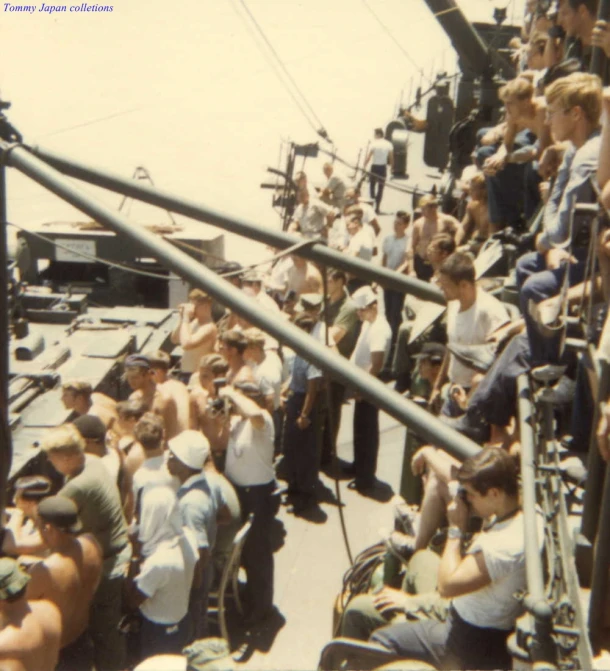 people sitting and standing on the side of boats