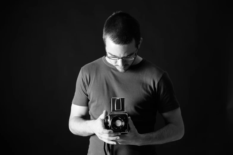 man in glasses holding an old camera taking a picture