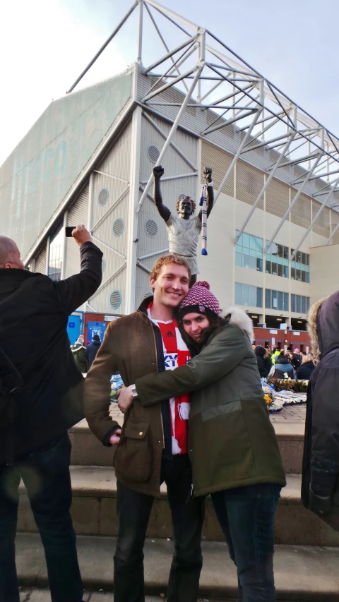 a couple of young people hugging each other in front of some steps