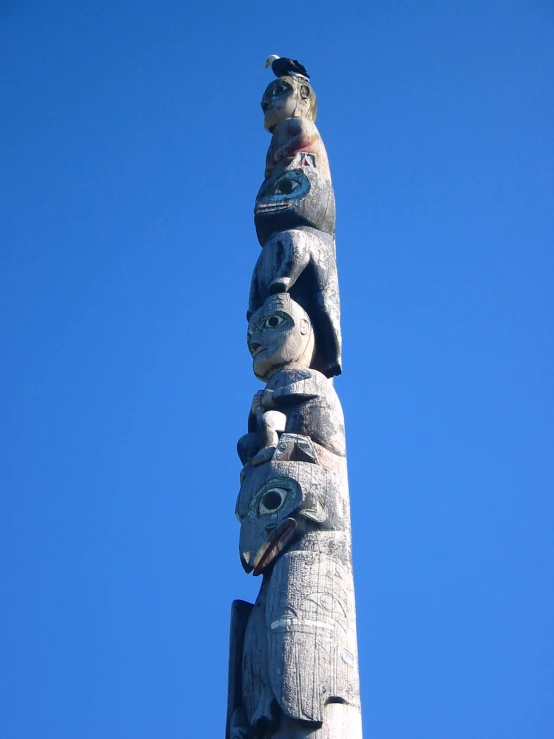 a totema statue made with two heads and two faces against a blue sky