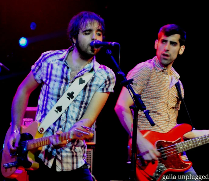 a pair of guys playing guitar and singing into a microphone