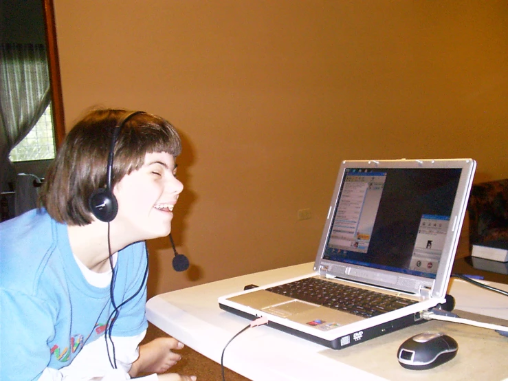 a young person with headphones sitting in front of a laptop