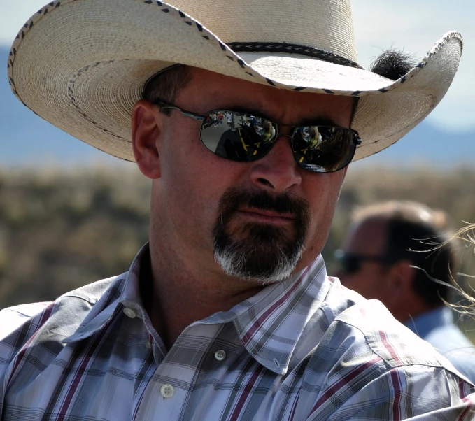 a man in a cowboy hat with two glasses on his head