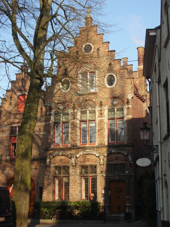 the large brick house is on the corner in front of the tree