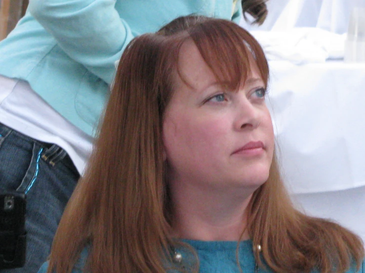 woman wearing blue looking to the side with her hair in half up