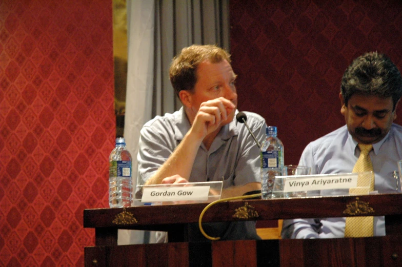 two men at a press conference in front of bottled water