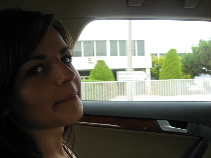 a woman sitting in the back seat of a car in front of an airport